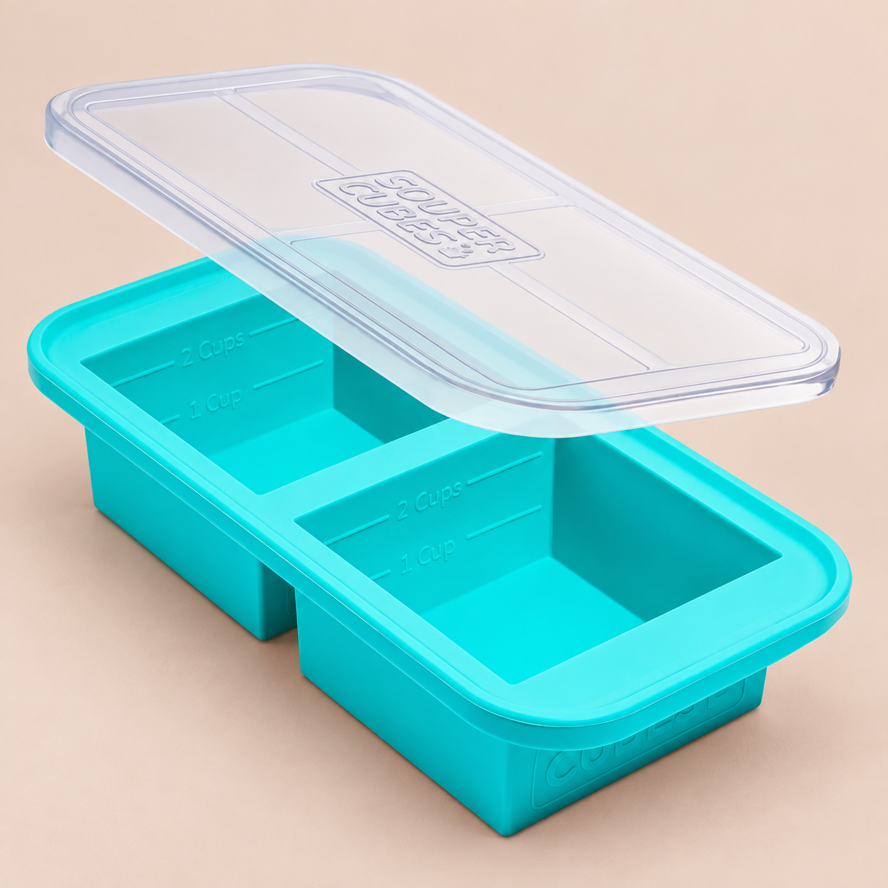 Aqua Blue Souper Cubes 2-Cup Food Freezing Tray with its clear lid on a warm beige background